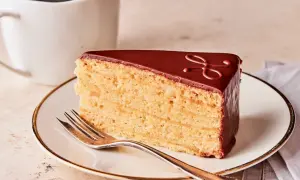 Ein Stück Schokoladenkuchen mit vielen Schichten, perfekt für ein Herrentorte Rezept. Dazu eine Tasse Kaffee.