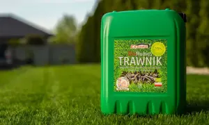 Zielony kanister z napisem "Humus Trawwnik" na tle bujnej, zielonej trawy. To naturalny nawóz, który pomoże Twojemu trawnikowi rozkwitnąć.