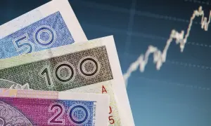 Polskie banknoty 50, 100 i 200 zł na tle wykresu giełdowego.
