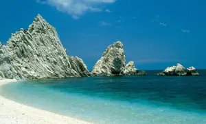 Spiaggia bianca e mare cristallino con faraglioni imponenti, un sogno per le località balneari Marche economiche.