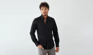 Mann in schwarzem Hemd und grauer Hose, mit gemustertem Kragen und Manschetten.
