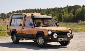 En orange Talbot Matra Rancho står parkerad på en grusväg med skog i bakgrunden.