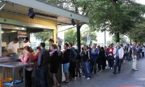 Długa kolejka do popularnego stoiska z kebabem w Berlinie. Ludzie cierpliwie czekają na swoje zamówienie, ciesząc się atmosferą miasta.