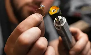 Manos de joyero puliendo un anillo de oro con un diamante. La herramienta de pulido tiene una placa de oro en su extremo.