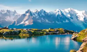 Lac alpin paisible reflétant les sommets enneigés du Mont-Blanc. Un campement discret et un randonneur contemplent ce paysage grandiose, parfait pour une randonnée tour du mont blanc.
