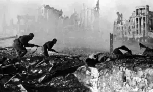 Soldater kämpar i ruiner. En fallen soldat ligger framför dem. Detta är en bild från slaget om Stalingrad, som idag heter Volgograd.