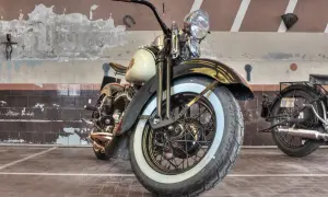 Klasyczny motocykl z białymi bokami opon, stojący w garażu.