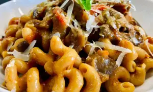 Un piatto invitante di pasta con melanzane, condita con un ricco sugo e scaglie di parmigiano.