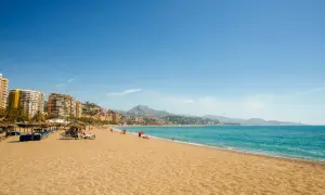 Playa con sombrillas y tumbonas, gente disfrutando del sol y el mar. ¡Unas de las mejores playas cerca de Madrid!