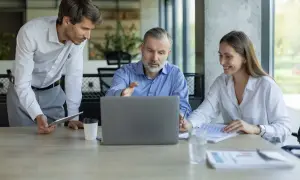 Professionisti discutono su come tutelarsi per affittare un negozio, analizzando contratti al computer.