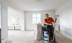 Målare med roller redo att måla bakom elementet i ett rum under renovering.