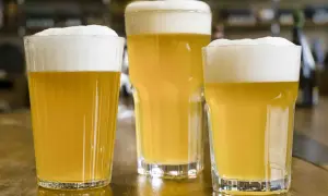 Tre bicchieri di birra dorata con schiuma bianca, pronti per essere gustati. Gli ingredienti della birra, acqua, malto e luppolo, si trasformano in questa bevanda rinfrescante.