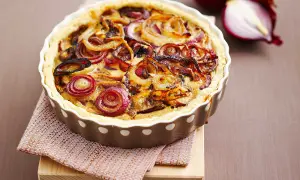 Tarte à l'oignon dorée et appétissante, garnie d'oignons caramélisés et d'une pâte croustillante. Un délice visuel et gustatif.