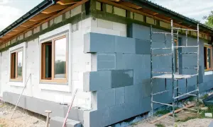 Budowa domu w toku. Szara warstwa izolacyjna na ścianie z białych pustaków. Sprawdź, jaka jest cena ocieplenia za 1m2 robocizna.