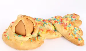 Una cuzzupa intrecciata con un uovo al centro, decorata con zuccherini colorati.
