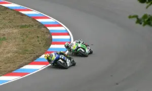 Dwóch motocyklistów ściga się na zakręcie toru wyścigowego.