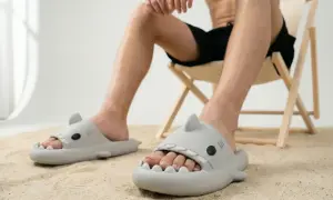 Mężczyzna w klapkach w kształcie rekinów siedzi na plaży. Czy klapki powinny być większe, by pomieścić wszystkie palce?