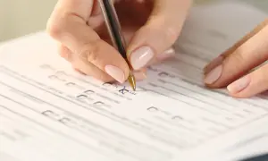 Dłoń z długopisem zaznacza "TAK" na formularzu, który może być wnioskiem o orzeczenie niepełnosprawności.