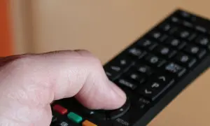 Dłoń trzymająca pilot do telewizora Samsung, naciskająca przyciski.