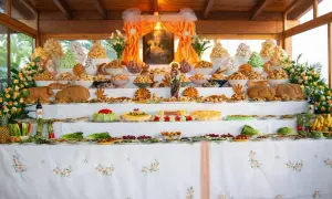 Un'abbondante tavolata ricca di dolci, pani e frutta, che celebra le tradizioni italiane con un'esposizione che ricorda un altare votivo.