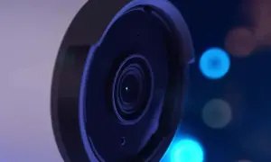 Gros plan sur l'objectif d'une caméra de surveillance, avec des lumières bleues floues en arrière-plan, évoquant le stockage vidéo surveillance.