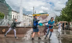 W drugi dzień świąt wielkanocnych młodzi ludzie oblewają się wodą przy fontannie, śmiejąc się i bawiąc.