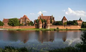 Potężny zamek w Malborku, odbijający się w wodzie. Ciekawostki o jego historii i architekturze budzą podziw.