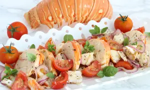 Aragosta alla catalana, un piatto fresco con code di aragosta, pomodorini, cipolla rossa e basilico, guarnito con una coda intera.