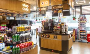 Wnętrze kawiarni Stop Cafe z ladą, ekspresem do kawy, półkami z napojami i przekąskami.