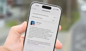 Dłoń trzyma iPhone'a z otwartym ekranem aktualizacji iOS 18.2.