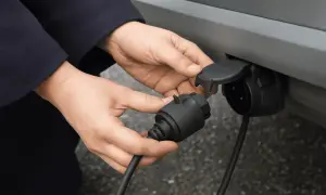 Mains de personne effectuant le branchement faisceau attelage sur feu arrière d'une voiture.