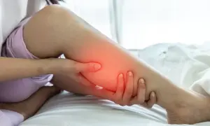 Une personne se tient la jambe, une zone rouge vif sur le mollet indiquant une douleur.