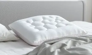 A white pillow with a textured surface rests on a bed, showing how a pillow should support you with its unique design for ultimate comfort.