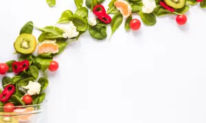 Kolorowe warzywa i owoce, takie jak kiwi, pomarańcza, papryka i pomidorki, tworzą kompozycję idealną dla diety wegańskiej.