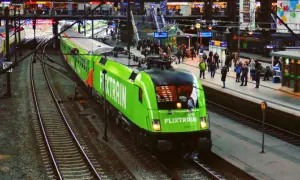 Ein grüner FlixTrain fährt in Berlin Hbf ein. Reisende warten auf dem Bahnsteig.