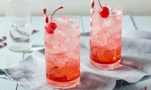 Erfrischende Crodino Rezepte: Zwei Gläser mit Eis, Kirschen und roten Strohhalmen.