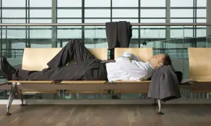 Biznesmen śpi na ławce w poczekalni lotniska, próbując pokonać jet lag. Ile trwa jet lag?