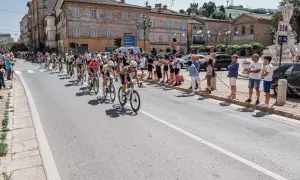 Ciclisti in gara durante il Giro d'Italia Marche, acclamati da spettatori festanti lungo la strada.