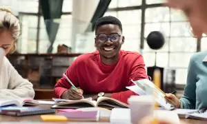 Jóvenes sonrientes estudiando juntos, una experiencia que inspira a estudiar en el extranjero.