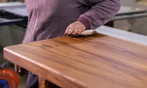 En hand gnider in ett träbord med linolja för att ge det en vacker lyster.
