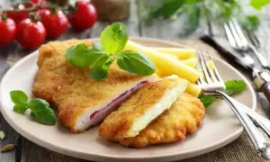 Schab po szwajcarsku, panierowany kotlet z szynką i serem, podany z makaronem i bazylią.