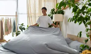 Frau richtet Bettwäsche, die nicht einlaufen kann, da sie aus Polyester ist.