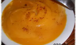 Aksamitna zupa z batatów, doprawiona szafranem i cynamonem, podana w białej miseczce z łyżką.