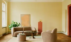 Ein Wohnzimmer mit gelben Wänden und einer grünen Decke, die frisch gestrichen wurde. Gemütliche Bouclé-Möbel laden zum Entspannen ein.