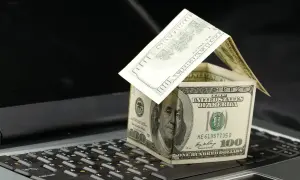 Dolarowy domek na klawiaturze symbolizuje koszty związane z posiadaniem nieruchomości, w tym podatek od nieruchomości.