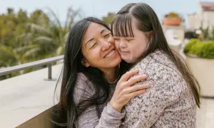 Abbraccio affettuoso tra due donne, una con sindrome di Down, che condividono un momento di gioia e amore.