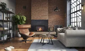 Przytulny, **soft loft** z ceglaną ścianą, palącym się kominkiem, wygodną kanapą i fotelem.