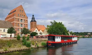Statek "Hoffnung" cumuje przy brzegu rzeki Łaby w Niemczech, obok zabytkowych budynków i kościoła.