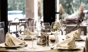 Elegancko nakryty stół z kieliszkami, serwetkami i przyprawnikami.