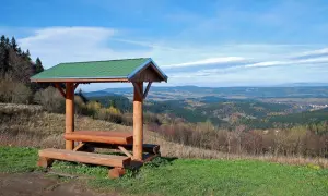 Drewniana wiata z ławami i stołem na tle malowniczego krajobrazu zieleniec góry.